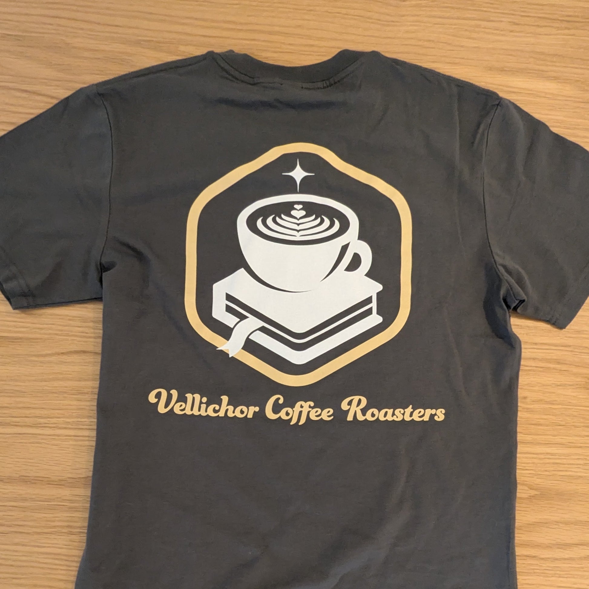 Black t-shirt with Vellichor Coffee Roasters logo on a wooden surface